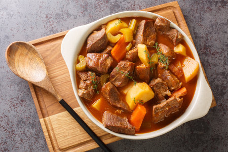 Hearty Irish inspired beef stew made with garlic, stock,  bacon, potatoes, carrots, and onions closeup in the pot on the table. Horizontal top view from aboveの写真素材