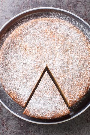 Yogurt cake or gateau au yaourt is a classic French baked good with icing sugar closeup in a plate on a table. Vertical top view from aboveの写真素材