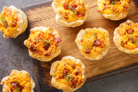 Homemade puff muffins with ham, vegetables and Cheddar close-up on a wooden board on the table....