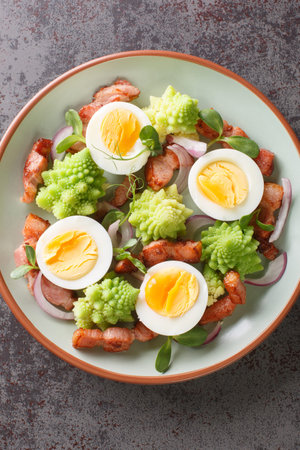 Delicious breakfast of romanesco cabbage, boiled eggs, fried bacon and microgreens close-up in a...