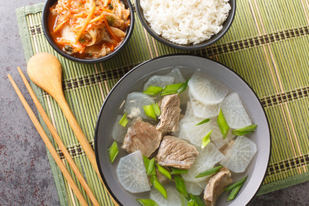 Seogogi Mu Guk Korean Beef and Radish Soup served with rice and kimchi closeup on the mat on the table. Horizontal top view from aboveの写真素材