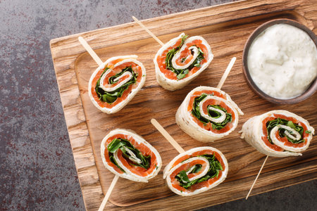 Appetizer of wrapped smoked salmon fillet, cream cheese and herbs in a flat bread close-up on a...