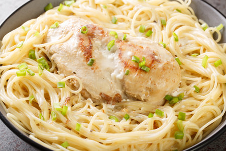 Tender cooked chicken in a creamy Italian flavored sauce and served on a bed of angel hair pasta closeup in the bowl on the table. Horizontalの写真素材