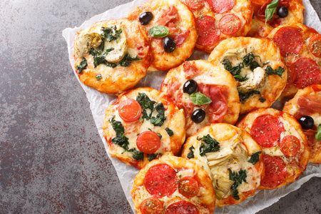 Italian Pizzette Mini Pizza Bites With Assorted Toppings close-up on parchment on the table. Horizontal top view from aboveの写真素材