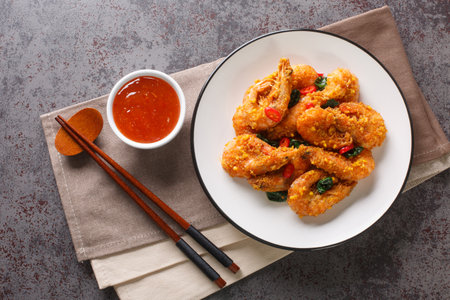 Crispy delicious fried shrimp with salted egg yolks, curry leaves and chili peppers served with chili sauce close-up in a plate on the table. Horizontal top view from aboveの写真素材