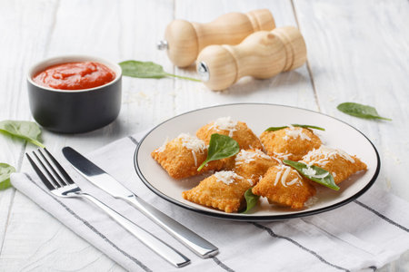 Breaded fried Italian ravioli with hot marinara tomato dipping sauce closeup on the wooden table. Horizontalの写真素材