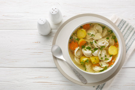 Soup with pelmeni dumplings a dish of Russian cuisine closeup on the bowl on the wooden table. Horizontal top view from aboveの写真素材