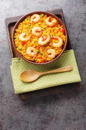 Flavorful Spanish yellow rice and shrimp with vegetables and spices closeup on the plate on the table. Vertical top view from aboveの写真素材
