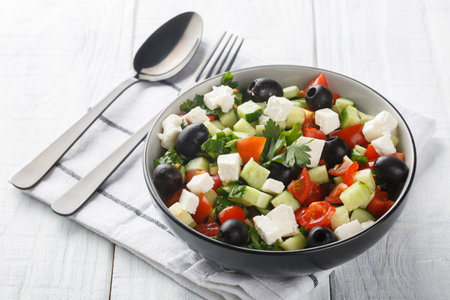 Coban Salatasi or Shepherds Salad is a simple yet delicious side dish made with tomato, cucumber, peppers, onion, herbs and cheese closeup in the bowl on the wooden table. Horizontalの写真素材
