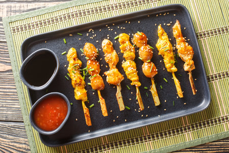 Delicious Japanese-style chicken skewers served with two sauces close-up on a plate on the table. Horizontal top view from aboveの写真素材