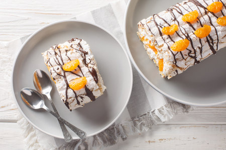 Gluten-free traditional Swedish dessert Budapest roll filled with whipped cream and tangerines close-up in a plate on the table. Horizontal top view from aboveの写真素材
