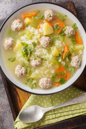 Crockpot Rice soup with meatballs, vegetables and herbs close-up in a bowl on the table. Vertical top view from aboveの写真素材