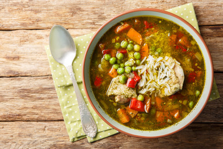 Aguadito de Pollo is a Peruvian cuisine, combining ingredients such as chicken, rice, vegetables and coriander in a tasty broth closeup on the bowl on the wooden table. Horizontal top view from aboveの写真素材