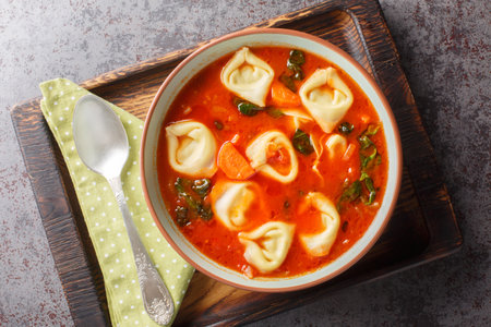 Delicious Creamy Tomato Tortellini Soup with spinach and vegetables closeup on the plate on the table. Horizontal top view from aboveの写真素材