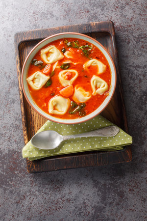 Vegetarian tomato tortellini pasta soup with vegetables and spinach close-up in a plate on the table.の写真素材