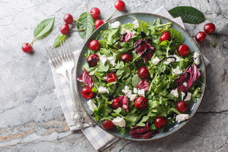 Fresh crispy salad with pickled cherries, arugula, radicchio and feta cheese dressed with balsamic dressing close-up in a plate on the table. Horizontal top view from aboveの写真素材