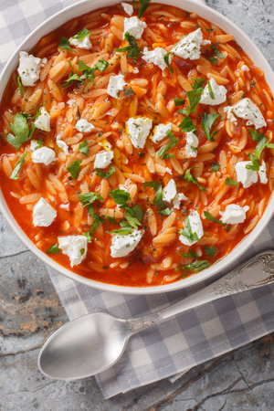 Mediterranean cuisine orzo pasta with spicy tomato sauce, feta, garlic, onion, carrots closeup on the plate on the table. Vertical top view from aboveの写真素材
