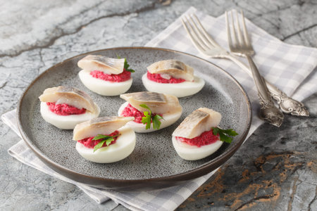 Festive deviled eggs stuffed with beets and herring close-up in a plate on the table. horizontal
