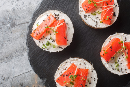 Smorrebrod traditional Danish sandwich with Black rye bread, salmon, cream cheese, sesame and micro...