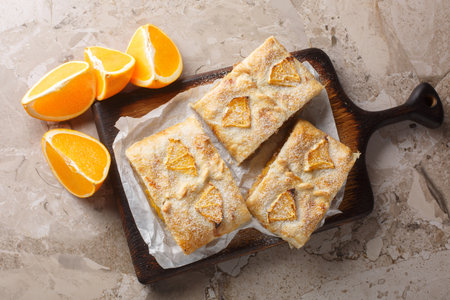 Orange strudel stuffed with walnuts, jam, raisins and fresh fruits close-up on a wooden board on the table. Horizontal top view from aboveの写真素材