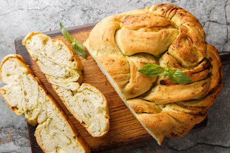 Savory braided pesto bread closeup on the wooden board on the table. Horizontal top view from aboveの写真素材