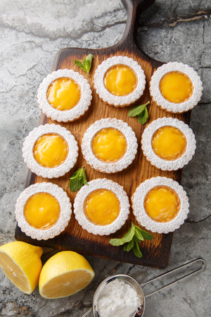 Delicious sweet lemon curd cookies sprinkled with powdered sugar closeup on wooden board on the table. Vertical top view from aboveの写真素材