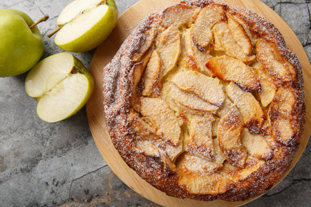 Caramelised apple clafoutis with vanilla and cinnamon close-up on a wooden board on the table. Horizontal top view from aboveの写真素材
