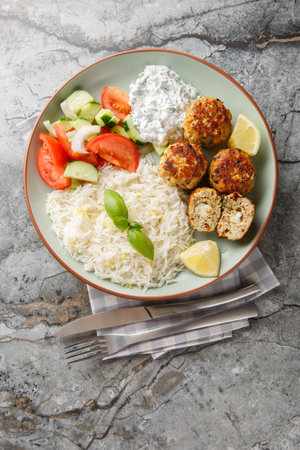 Greek chicken meatballs with feta cheese served with lemon rice and vegetable salad close-up in a plate on the table. vertical top view from aboveの写真素材