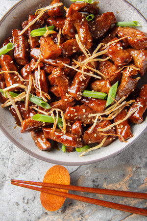 Ginger beef with crispy beef, a lightly sweet sauce, green onion and caramelized ginger closeup in...