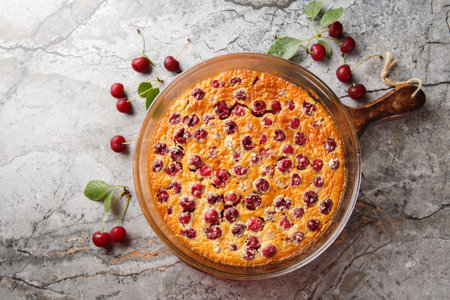 Cherry clafoutis French favorite is a sort of baked custard, studded with fresh cherries, and scented with vanilla close-up in a baking dish on the table. Horizontal top view from aboveの写真素材
