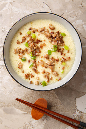 homemade steamed egg with crispy minced pork and green onion closeup in the bowl on the table. Vertical top view from aboveの写真素材