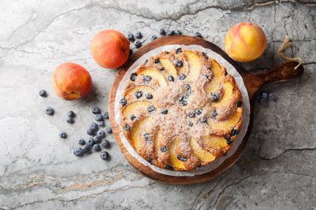 Homemade pie with fresh peaches and blueberries close-up on a wooden board on the table. horizontal top view from aboveの写真素材