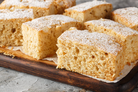 Fluffy sponge Applesauce cake with ginger sprinkled with powdered sugar close-up on a wooden board...