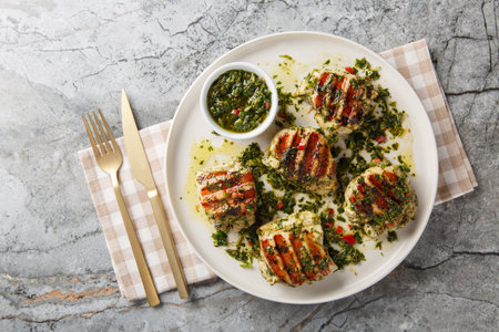 Grilled chicken thighs with chimichurri sauce made with garlic, herbs and vegetable oil close-up in a plate on the table. Horizontal top view from aboveの写真素材