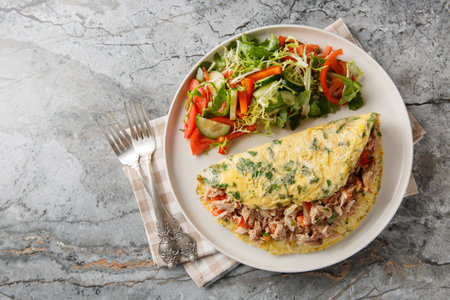 Full breakfast Omelet with tuna and pepper served with vegetable salad close-up in a plate on the table. Horizontal top view from aboveの写真素材