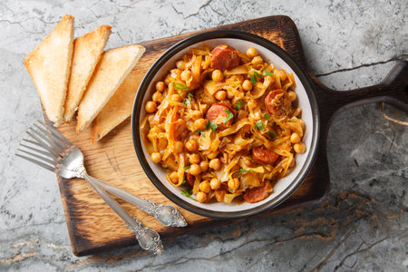 Delicious winter food: cabbage stewed with chickpeas, chorizo and paprika close-up in a plate on the table. Horizontal top view from aboveの写真素材