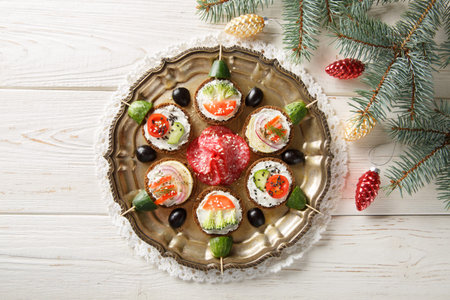 Christmas canapes decoration idea with cream cheese and vegetables close-up in a plate on the table....