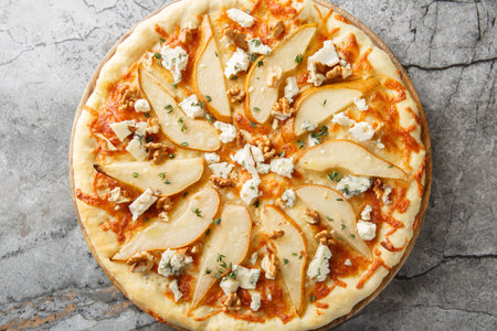 Honey pear pizza with blue cheese, nuts, mozzarella and thyme close-up on a wooden board on the table. Horizontal top view from aboveの写真素材