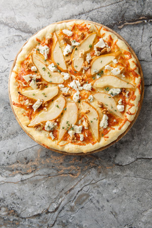Pizza with pear, blue cheese, walnuts and thyme close-up on a wooden board on the table. Vertical top view from aboveの写真素材