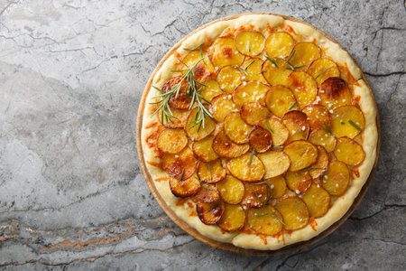 Vegetarian Potato rosemary pizza sprinkled with coarse salt and baked until crispy close-up on a wooden board on the table. Horizontal top view from aboveの写真素材