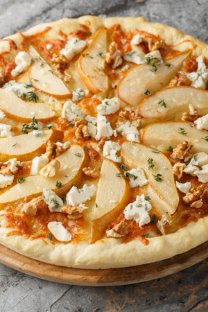 Pizza with pear, blue cheese, walnuts and thyme close-up on a wooden board on the table. Verticalの写真素材