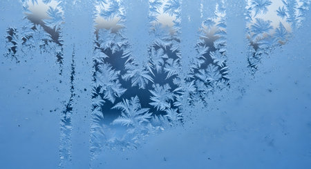 Frosty natural pattern on winter window glass. Abstract background.の素材