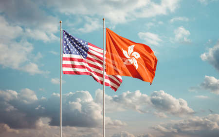 Hong Kong and USA flags waving at blue sky background. Concept of international HK American relations.の写真素材