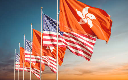 Hong Kong and USA flags waving at cloudy sky background. Concept of international HK American relations.の写真素材