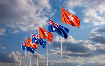 The Aussie and Hong Kong flags fly together in the wind against the cloudy blue sky background. The concept of cooperation and competition in economics and politics. Flag of the Australia to the left of Hong Kong.の写真素材