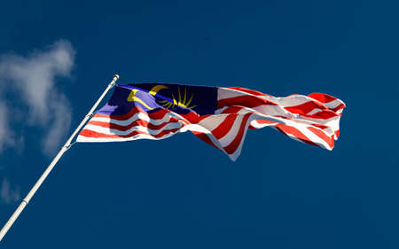 Malaysian national flag waving in the wind against blue sky background low angle close up. Malaysia Kuala Lumpur symbol.の写真素材