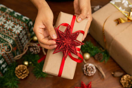 Hands of a woman holding a Christmas present. The gift has a red ribbon and a starの写真素材