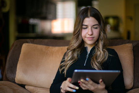 Relaxed girl sitting on the living room sofa with her tablet