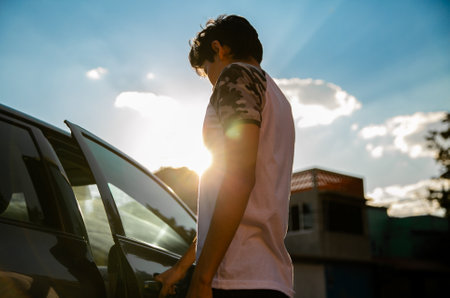 Back view of a Young man opening a car door. He has a white shirtの写真素材