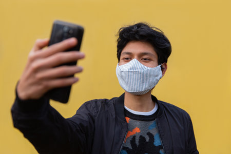 Young Men with mask, He has his phone in his hands, taking a selfieの写真素材